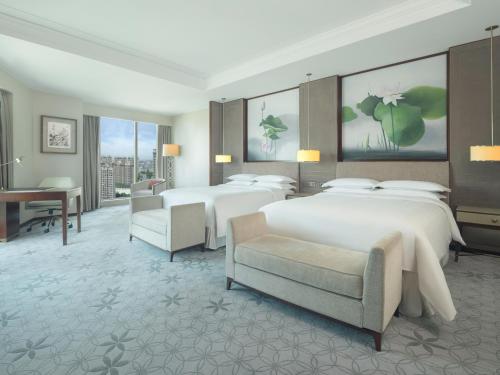 嘉定区にあるシェラトン 上海 嘉定 ホテルのベッド2台とデスクが備わるホテルルームです。