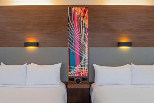 two beds in a hotel room with a painting on the wall at Aloft New Orleans Downtown in New Orleans