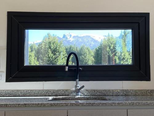 um lavatório de cozinha com uma janela com vista para a montanha em Meliquina Home em Villa Meliquina