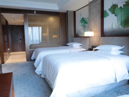 two beds in a hotel room with white sheets at Sheraton Shanghai Jiading Hotel in Jiading