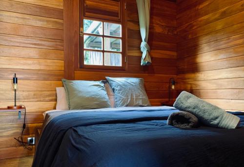 a bedroom with a bed with wooden walls and a window at Kaya Lodge in Basse-Pointe