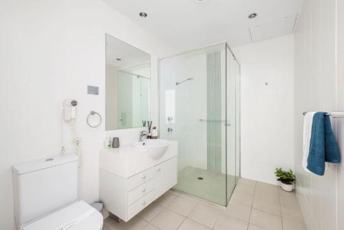 een witte badkamer met een wastafel en een douche bij 514 Oaks Pacific Blue Townhouse in Salamander Bay
