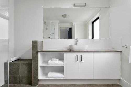 a white bathroom with a sink and a mirror at Quest West End in Perth