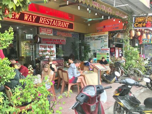 a group of people sitting outside of a restaurant at New Way Hotel in Cat Ba