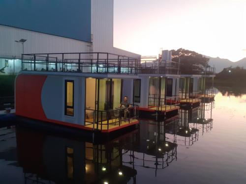a house boat in the water next to a building at ริมกว๊านชาเลย์ รีสอร์ทแอนด์คาเฟ่ Rimkwan Chalay Resort and Cafe in Ban Rong Ha