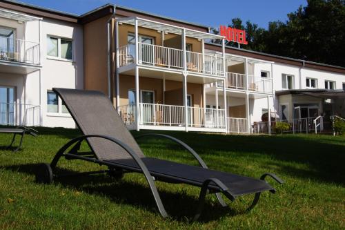 a bench in the grass in front of a building at Hotel am Untersee in Bantikow