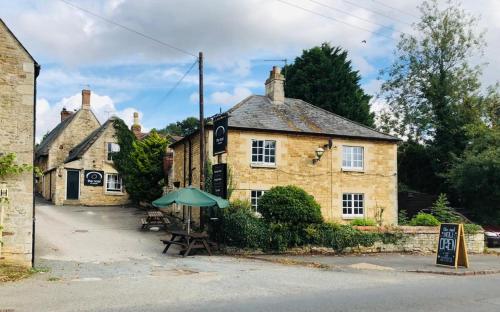 an old stone building with an umbrella in front of it at The Noel At Whitwell 