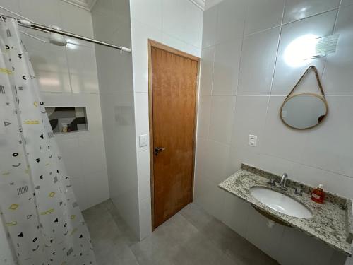 a bathroom with a sink and a shower and a mirror at Canto do Forte in Praia Grande