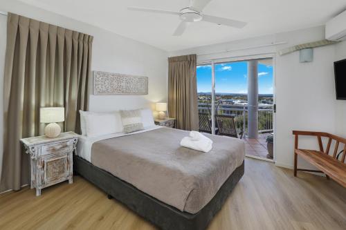 1 dormitorio con 1 cama grande y balcón en Beachside Resort Kawana Waters en Buddina