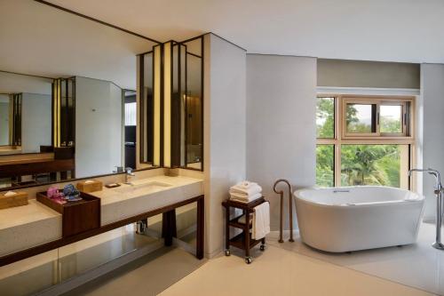 a bathroom with a tub and two sinks and a large mirror at Sheraton Grand Xishuangbanna Hotel in Jinghong
