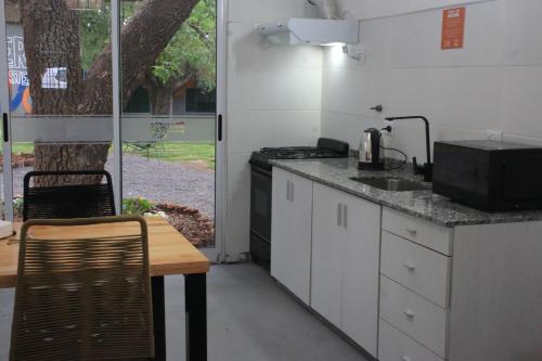cocina con encimera, fregadero y mesa en BROTHERS HOSTEl en Villa Allende