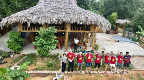 a group of people standing in front of a hut at Lakeview Homestay Vu Linh in Yen Bai