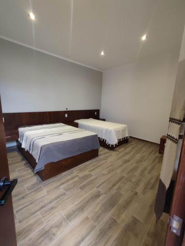 two beds in a large room with wooden floors at Casa Mictlan. Habitaciones en el Centro de Mitla. in San Pablo Villa de Mitla