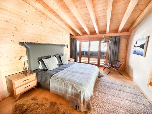 een slaapkamer met een bed en een houten plafond bij Sumptuous Chalet with Breathtaking views by GuestLee in Gryon