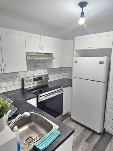 a kitchen with a sink and a white refrigerator at Spacieux Appartement de 3 Chambres downtown in Montréal