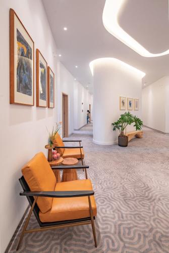 a lobby with orange chairs and paintings on the wall at Wuyu Hotel - Chongqing Liangjiang Happiness Plaza & Xingfu Square & GuangdianYuan metro in Chongqing
