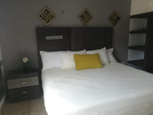 a bedroom with a white bed with a yellow pillow at La Luna in Cancún