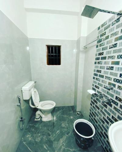 a bathroom with a toilet and a sink and a window at Hotel Abhinov in Dibrugarh