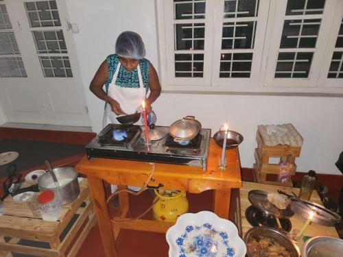 Uma mulher na cozinha a preparar comida com uma vela acesa. em CEYLON STAYZ em Colombo