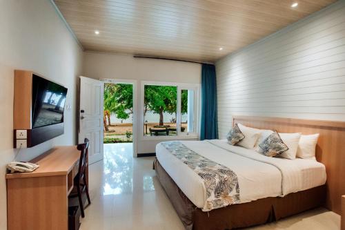 a bedroom with a bed and a desk and a television at Sylvia Hotel & Resort Komodo in Labuan Bajo