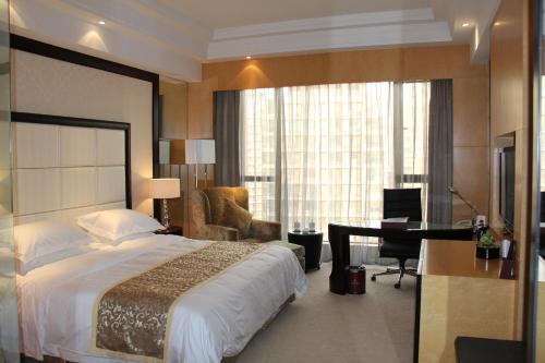 イ坊市にあるRamada Plaza Weifangのベッド1台、デスク、ベッドルーム1室が備わります。