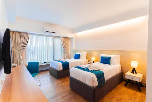 a hotel room with two beds and a television at Copenhagen Residences - Ormoc in Ormoc