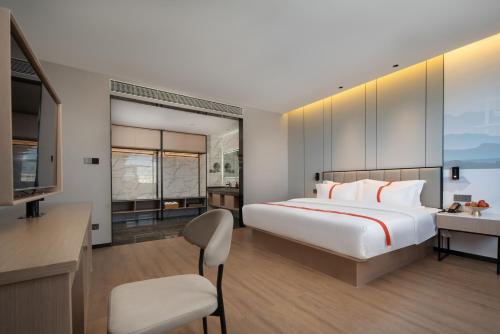 騰衝的住宿－格林东方酒店(腾冲东湖公园店)，一间卧室配有一张床、一张书桌和一台电视