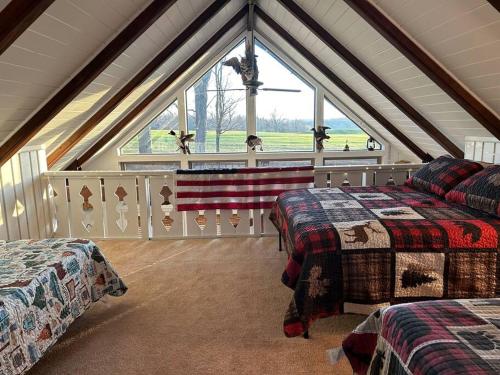 a attic bedroom with two beds and a large window at Cozy Indian Lake Chalet on Golf Course with Arcade/Gameroom in Stoystown