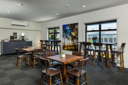 un restaurante con mesas, sillas y ventanas en The Abbott Boutique Hotel en Cairns