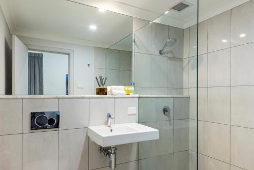 a bathroom with a sink and a mirror at The Abbott Boutique Hotel in Cairns