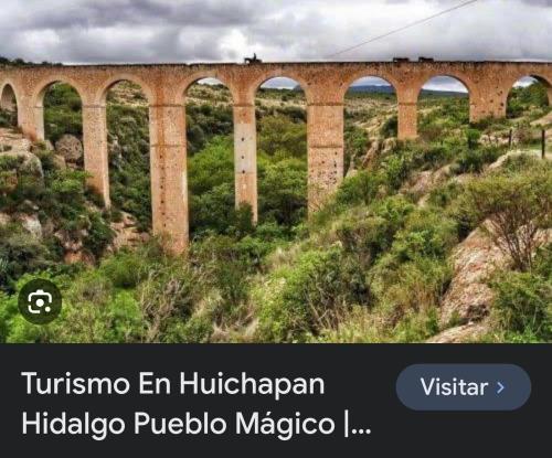 a bridge on top of a hill with trees and bushes at los pepes in Huichapan