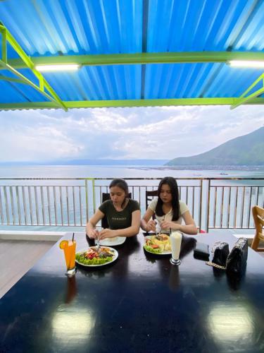 Agape Hotel Haranggaol في Haranggaul: كانتا جالستين على طاولة مع أطباق من الطعام