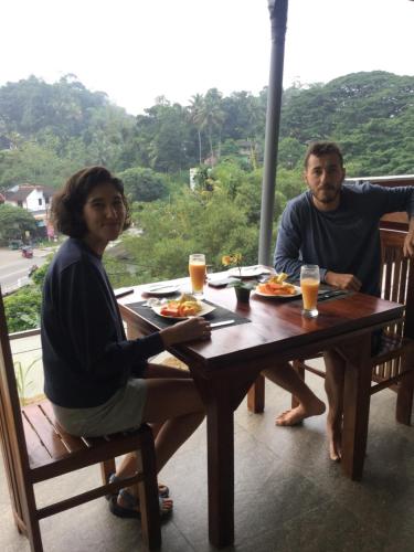 a man and a woman sitting at a table with food at Kandyan Lounge in Kiribatkumbura