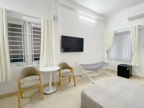 a white room with a bed and chairs and a tv at SAIGONESE Studio in Ho Chi Minh City