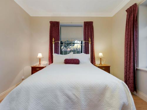 una camera da letto con un grande letto bianco con tende rosse di Lake Bywater Cottage a Walker Flat