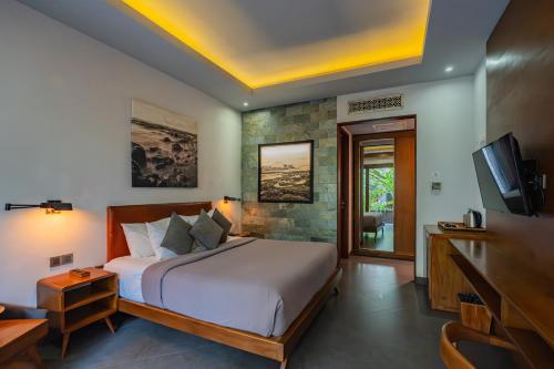 Un dormitorio con una cama grande y un televisor. en Akana Boutique Hotel, en Sanur
