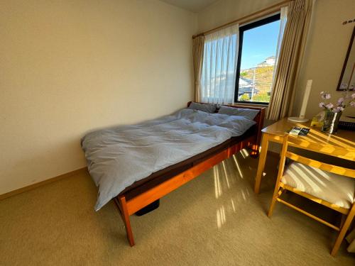 a bed in a room with a desk and a window at South Wind Chalet in Itoshima