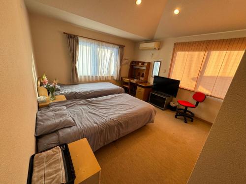 a hotel room with two beds and a desk at South Wind Chalet in Itoshima