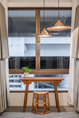 a table and a stool in front of a window at Unplugged at Bangrak Design Hostel in Bangkok