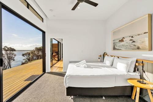 a bedroom with a bed and a view of the ocean at Freycinet Coastal Retreat in Coles Bay