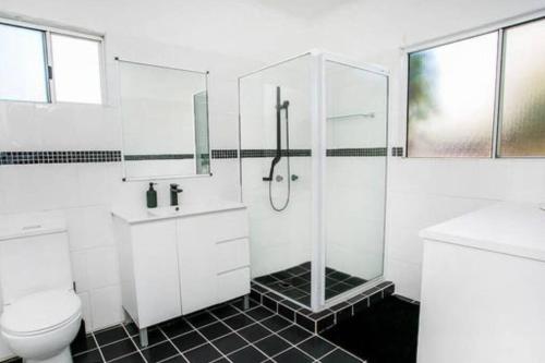 uma casa de banho branca com um chuveiro e um WC. em Bet you’ll love butler em Mount Isa