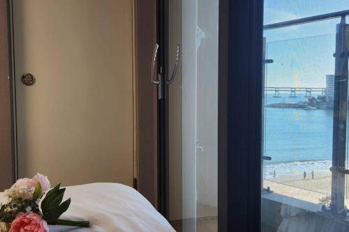 a room with a bed with a view of the beach at 1 second to Gwanganbeach in Busan