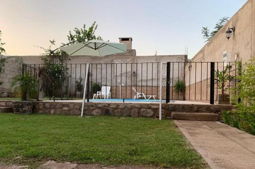 a fence with an umbrella in a yard at Hermosa casa con piscina . in La Rioja