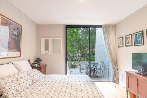 a bedroom with a bed and a television and a patio at Sterling 1 Self-Catering in Sydney