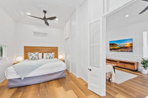 a white bedroom with a bed and a ceiling fan at Elegant 3-Bed 2-Bath Cottage: Classic Charm with a Modern Twist in Townsville