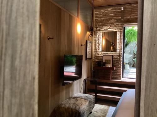 a room with a tv and a ottoman and a window at The Opposite Place in Melaka