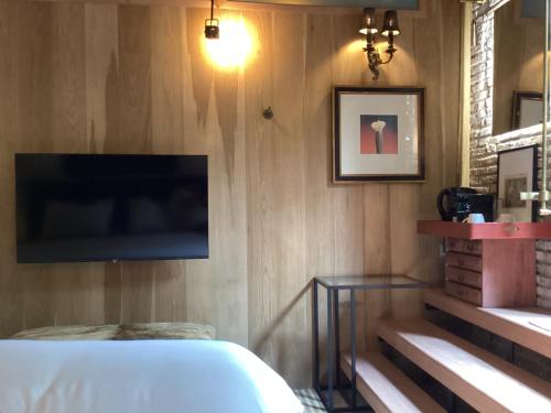 a bedroom with a bed and a tv on a wall at The Opposite Place in Melaka