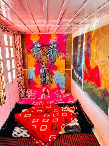Cette chambre comprend un lit orné d'une peinture murale. dans l'établissement Trishul Cafe, à Tosh