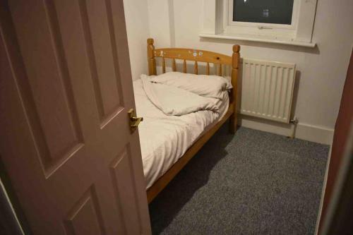 ein kleines Bett in einem Zimmer mit Fenster in der Unterkunft Lovely 3 Bedroom House South Norwood London in Norwood