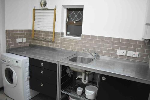 a kitchen with a sink and a washing machine at Lovely 3 Bedroom House South Norwood London in Norwood